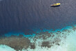 © AmazingAerialAgency - Aerial view of a boat drifting on the tranquil turquoise and deep blue waters near the coral reef, Pink Beach, East Nusa Tenggara, Indonesia.