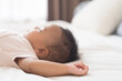 © amorn - Newborn health care. Newborn baby sleeping on bed. Hands and soft skin of newbord baby during lying on white blanket