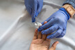 © InveStock - Close-up of healthcare worker wearing gloves applying cotton on patient’s finger after capillary blood test procedure.
