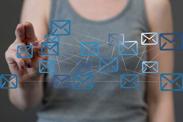 Stock photo of a woman's hand interacting with a digital network of email icons, representing communication and connectivity.