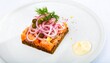 © Hanako - Smoked salmon tartare on dark bread, garnished with red onion, capers, dill, and aioli