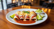 © virginiaf99 - Sizzling Cheesy Enchiladas with Red Sauce Served with Guacamole and Limes on a White Plate