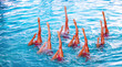 © Vital - Group of athletes performing synchronized swimming routine in clear blue pool water during bright daylight