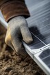 © misunderst00d - Gloved hand adjusting monocrystalline solar panel against soft clay background. Closeup view with focus on panel