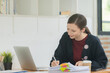 © Songsak C - Portrait of a happy businesswoman working with a laptop in an office.