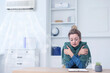 © New Africa - Broken air conditioner or temperature set too low. Woman with scarf freezing at workplace in office