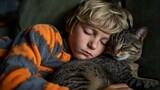 A young boy rests with his eyes closed, cuddling a cat on a soft couch, creating a warm atmosphere.