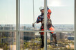 © Maria Moroz - Man industrial climber or window cleaner on a rope washing skyscraper windows.