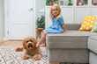 © KseniaJoyg - Fluffy Dog Labradoodle or goldendoodle dog Relaxing with child girl on the couch in home with a natural modern interior