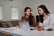 © Parichat - Businesswomen discussing strategy using laptop and documents at home