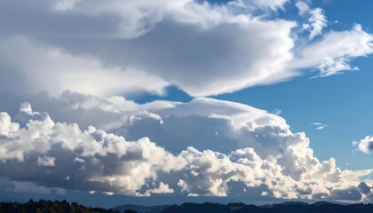 Dramatic, fluffy white clouds float in a bright blue sky above tree-covered hills