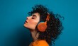 © Octopus - A young woman with curly hair is immersed in music while wearing bright orange headphones against a blue background