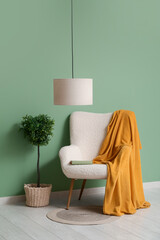 Poster - hanging lamp, decorative tree and armchair with plaid near green wall in room