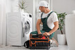 © Pixel-Shot - Male plumber with bag of tools fixing washing machine in bathroom