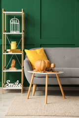 Poster - interior of cozy living room with sofa, shelf unit and autumn decor
