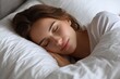 © VolumeThings - Calm woman rests on a soft pillow in bed Attractive single female enjoys a healthy sleep on fresh linens and an orthopedic mattress Theme of relaxation and sweet dreams