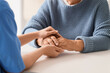 © Pixel-Shot - Caregiver with senior woman holding hands at table, closeup