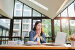 © ThawKyar - Asian businesswoman is working in office. She is very excited and happy that his business is successful and points at laptop screen. Businesswoman concept.