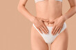 © Pixel-Shot - Young woman in panties on beige background, closeup. Menstruation concept