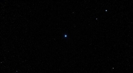 A clear night sky showing a few distant stars against a deep black background. A minimal concept of space, astronomy, and the vast universe.