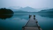 © MDRAFIQUL - Misty lake with a wooden pier extending into the calm water. Foggy mountains, serene and melancholic landscape, tranquil nature.