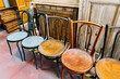 © irissca - Assorted secondhand wooden chairs arranged in a row inside a vintage furniture store. Circular economy, sustainable furniture, reuse economy, eco-conscious living