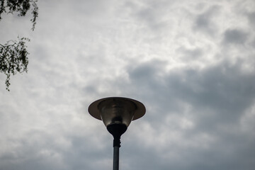 low-angle view of a weathered street lamp standing tall beneath a dramatic, overcast sky with soft, 