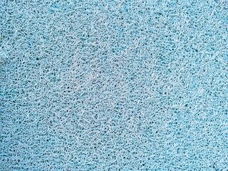 Close-up texture of a light blue synthetic mesh surface with intricate intertwined loops. Abstract background suitable for industrial, creative, or decorative design projects.