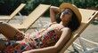 © j_everton - A relaxed woman wearing sunglasses and a hat, lounging on a deckchair in the sun
