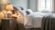 © Владимир Platon - A cozy and inviting bedroom interior with a soft, warm ambiance. The large bed is made with plush white bedding and a textured gray throw blanket, creating a comfortable and relaxing feel