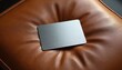 © Vadym - Minimalist brushed metal card mockup rests on textured tan leather chair. Shiny steel rectangle has brushed surface, conveying modern elegance and industrial feel. Smooth luxury design.