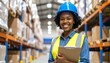 © IKetut - Portrait of a confident African American female worker in a hard hat and safety vest, managing inventory in a large warehouse