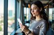 © starush - Woman using smartphone in modern office setting with large windows and city view
