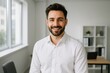 © Bijac - Confident young professional man with beard smiling warmly in modern minimalist office setting