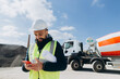 © dsheremeta - Construction engineer using smartphone at concrete production plant