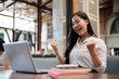 © PaeGAG - Excited businesswoman celebrating success while working on laptop in modern office