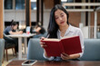 © PaeGAG - Young asian businesswoman reading a book in a modern coworking space