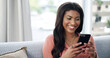 © peopleimages.com - Girl, phone and happy for texting on couch, relax and contact on web chat for online dating at home. African woman, smartphone and smile with mobile app, meme or social network on sofa at apartment