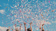 © Довидович Михаил - High school graduates celebrate by tossing colorful confetti into the sky against a backdrop of blue