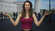 © Krakenimages.com - Young woman presses palms together at the leaning tower of pisa building on a busy street outdoors; serenity.