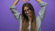 © Krakenimages.com - Young hispanic woman wearing glasses and striped shirt forms heart shape with hands in purple studio setting; love affection joy.