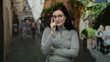 © Krakenimages.com - Woman with glasses standing outdoors on a bustling street, surrounded by blurred people in an urban environment, conveying a casual and relaxed atmosphere.