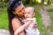 © unai - Latin mother kissing her baby daughter in a park
