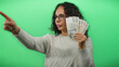 © Krakenimages.com - Woman holding czech koruna banknotes against a green background, pointing forward confidently in a casual sweater, embodying themes of finance and currency in an isolated setting.
