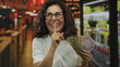 © Krakenimages.com - Woman holding mexican pesos gestures for silence in a vibrant restaurant setting, embodying secrecy, finance and culture with a hint of humor, creating an intriguing indoor scene.