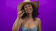 © Krakenimages.com - Middle-aged hispanic woman in bikini with hat over purple background smiling.
