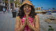 © Krakenimages.com - Woman in bikini with pink lei and straw hat smiling joyfully at beach promenade with blurred seaside background on a sunny day.