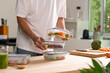 © amenic181 - Man preparing healthy homemade meal prep in food container with fresh food at home.