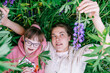 © Iryna - Child with Down syndrome with caregiver lying in meadow holding lupines