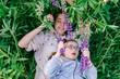 © Iryna - Teacher and child with Down syndrome lying in grass holding lupine flowers